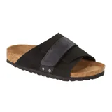 Sandalia Birkenstock modelo Kyoto, color negro, confeccionada en gamuza con una banda ancha ajustable mediante cierre de velcro y detalles de remaches metálicos. Presenta plantilla anatómica de corcho y suela de goma.