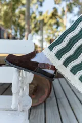 Zueco marrón de cuero con hebilla lateral y suela de goma.