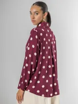 Camisa de manga larga en fibrana color bordó con estampado de lunares grandes en color crema. Presenta cuello camisero y cierre frontal de botones.