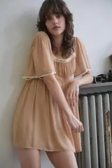 Vestido corto color tostado de escote cuadrado y mangas cortas, con detalles de encaje a contraste en el escote y dobladillos. Presenta diseño cruzado en la espalda.