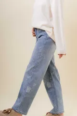 Pantalón de jean de corte recto y relajado, con tiro medio-alto. Presenta un estampado floral sutil en tonos claros sobre la base de denim azul y cuenta con interior forrado para mayor abrigo.