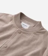 Campera bomber masculina de terciopelo cotelé color beige, con cuello redondo, mangas largas, cierre frontal de botones forrados, bolsillos laterales y terminaciones de elástico en puños y cintura.