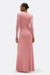 Vestido largo de jersey color rosado, con profundo escote en V, mangas largas ajustadas y detalle de drapeado frontal que nace de una flor bordada a mano en la cintura.