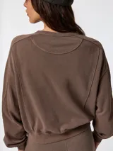 Buzo oversize marrón con cuello redondo, detalles de costuras visibles y puños y cintura de rib elástico.