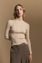 Polera de tejido acanalado con cuello alto, corte ajustado al cuerpo y mangas tres cuartos con terminaciones onduladas en los puños.
