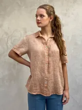 Camisa de manga corta, color tostado, con cuello camisero y botones frontales. Presenta una textura visiblemente arrugada, característica del lino.