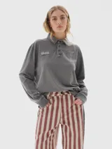 Chomba de manga larga con efecto lavado, cuello tipo polo con cartera de botones y estampado gráfico en el pecho.