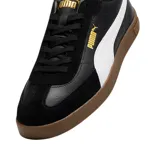Championes Puma modelo Club Li Era, con diseño de perfil bajo en color negro, franja lateral blanca característica de la marca y suela de goma color caramelo. Presenta detalles en dorado en el logo lateral y la lengüeta.