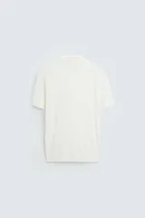 Polo de punto negro, manga corta, con cuello solapa y cierre frontal de tres botones. Presenta un calce regular y acabados en rib en mangas y ruedo.