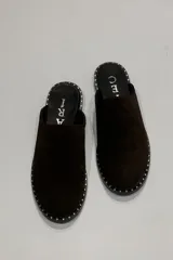 Zuecos de gamuza color marrón chocolate con suela plana y detalle de tachas pequeñas alrededor de la suela.