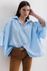 Camisa celeste de algodón con corte amplio, cuello camisero y mangas largas con puños abullonados.