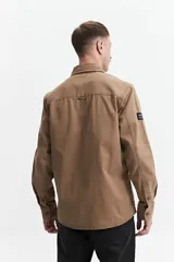 Sobrecamisa verde militar de twill de algodón, con cuello clásico, cierre frontal con botones a tono, dos bolsillos tipo parche con solapa abotonada en el pecho, mangas largas con puños abotonados y corte recto.