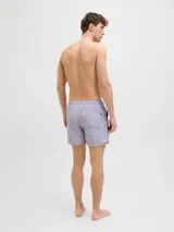 Short de baño de tiro medio en color lila, con cintura elástica y cordón ajustable. Presenta un diseño minimalista con el logo de la marca estampado en la parte inferior derecha.