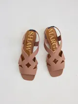 Sandalia de diseño geométrico con tiras cruzadas en color tostado, punta cuadrada y taco bajo. Presenta una plantilla con diseño de madera y logo de la marca.