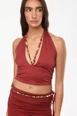 Top halter color bordó con escote profundo y tirantes decorados con cuentas artesanales.