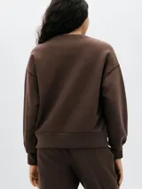 Buzo color crema de algodón, de corte holgado, con cuello redondo y mangas largas. Puños y ruedo acanalados.