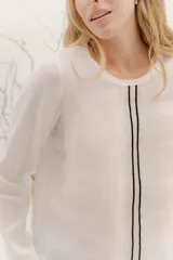 Remera de manga larga con escote a la base, color blanco, con un bordado central de dos líneas negras verticales en la parte delantera. La parte delantera es de lino y la espalda de algodón con spandex.