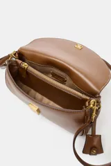 Bolso bandolera de formato alargado en color negro, con solapa frontal y cierre metálico. Incluye una correa ajustable de tejido en color crudo y herrajes dorados.