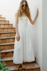 Vestido midi blanco de escote recto y tirantes finos ajustables. Presenta un torso elástico tipo nido de abeja con detalle de flores bordadas al tono en la parte superior y una falda de caída fluida con bolsillos laterales ocultos.