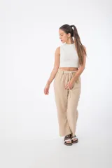 Pantalón de tela color beige, con cintura alta elastizada y cordón ajustable.