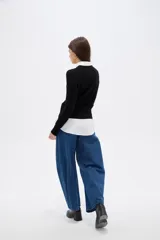 Saco de punto al cuerpo, color negro, con cuello redondo, manga larga y cierre frontal con botones pequeños.