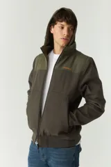 Campera softshell verde con capucha removible, cierre frontal y bolsillos con cierre.