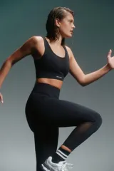 Calza deportiva negra, tiro alto, corte 7/8 y paneles de mesh en la parte inferior de la pierna.