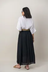 Pollera larga de color marrón, confeccionada en tela liviana con textura sutil y diseño plisado. Incluye un cinto rústico trenzado.