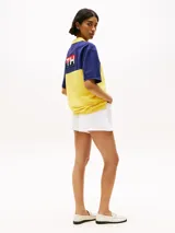 Chomba Tommy Hilfiger de corte amplio, con diseño color block en azul y amarillo, cuello clásico, cartera de tres botones, logo bordado en el pecho y logo oversize en la espalda.