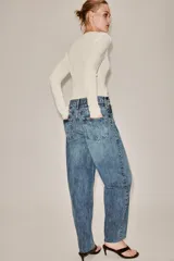 Jeans de tiro alto con corte tapered y largo al tobillo. Presenta cinco bolsillos, trabillas en la cintura, cierre frontal con cremallera y botón, y detalle de raya planchada en el delantero.