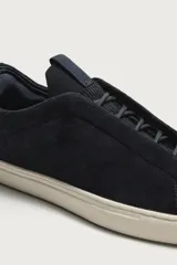 Zapatilla de piel con acabado en serraje de color gris, diseño de cordones ocultos y suela de goma en contraste de color blanco.