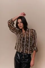 Blusa roja con estampado de piel de serpiente, escote en V con cordones y mangas 3/4 con puños elásticos.