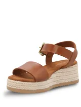 Sandalias Hush Puppies modelo Lili, color marrón, con plataforma de yute y suela de caucho. Presentan una tira ancha en el empeine y una correa ajustable al tobillo con hebilla metálica dorada.