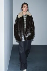Chaqueta de efecto cuero color marrón oscuro con acabado brillante, cuello de solapa con aplicación de pelo sintético extraíble, manga larga con trabillas, bolsillos frontales de plastrón con solapa y cierre frontal con cremallera y botones a presión.
