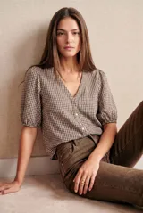 Blusa de algodón con estampado de cuadros vichy en tonos marrón y blanco, con escote en V, cierre frontal de botones y mangas cortas abullonadas con puños elásticos.