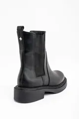 Bota tipo Chelsea de cuero negro, con paneles elásticos laterales y suela de goma con plataforma baja.