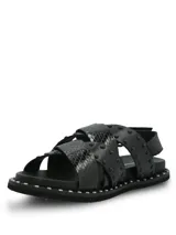 Sandalias negras de cuero con diseño de tiras cruzadas, decoradas con tachas metálicas. Poseen ajuste mediante hebilla lateral y suela de goma con detalle de tachas en el borde.