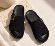 Sandalias planas de color beige con diseño de tira ancha en el empeine, hebilla metálica ajustable lateral y plantilla anatómica.