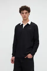 Remera polo de manga larga azul con cuello camisero blanco y cierre frontal de botones ocultos. Presenta un pequeño bordado con el texto "uniform" en el pecho y calce relajado.