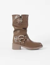 Bota corta de cuero vegano color marrón, con diseño de caña arrugada, hebilla decorativa en la parte superior y arnés metálico con hebilla en el tobillo. Cuenta con un taco cuadrado de altura media.