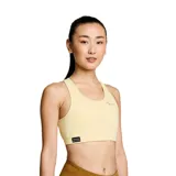 Top deportivo Saucony Fortify color amarillo pálido, con tirantes cruzados en la espalda y logo reflectante en el frente.