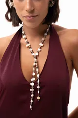 Corbatín largo tipo lazo compuesto por cuentas de nácar, discos de piedra hematite en tonos dorados y plateados, y mostacillas. Presenta una estructura ajustable con cadena de acero quirúrgico.