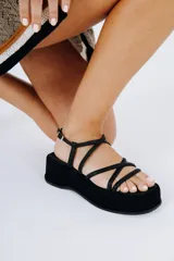 Sandalias negras de cuero vacuno, con plataforma de 5 cm y tiras finas cruzadas sobre el empeine.