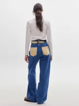 Pantalón jean de tiro alto y corte pinzado, con perneras de caída suelta y levemente anchas en el bajo. Posee pasador con hebilla en la parte trasera.