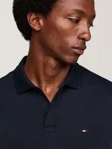 Chomba Tommy Hilfiger de corte regular, color azul marino, confeccionada en algodón. Presenta cuello tipo polo, cartera de dos botones y logo bordado en el pecho.