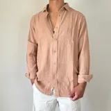 Camisa de lino con corte oversize, cuello clásico y cierre frontal con botones. Presenta mangas largas con puños arremangados y una textura rústica característica del tejido.