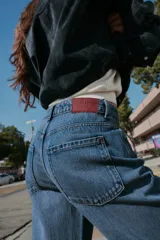 Jeans de tiro alto con diseño de cinco bolsillos, pernera recta y corte largo. Presenta cierre frontal con cremallera y botón metálico.