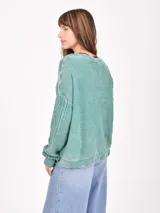 Buzo de tejido de punto con diseño de ochos, color rosado, con escote en V y mangas largas.