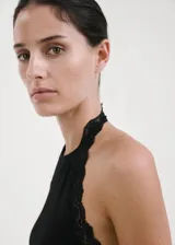 Top negro de algodón con diseño entallado, cuello halter y ribetes de encaje en los hombros y cuello. No incluye mangas.