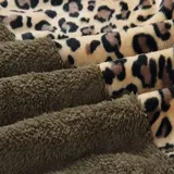 Buzo tipo canguro de polar, con diseño combinado en animal print de leopardo en la parte superior y color gris claro en la parte inferior. Cuenta con capucha, cordones ajustables y cierre frontal.